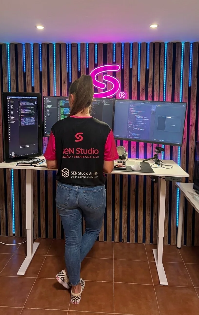 Sylvia trabajando de pie en su estudio, con la S de neón
